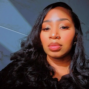 Close-up of a woman with long black hair and glowing skin in soft sunlight.