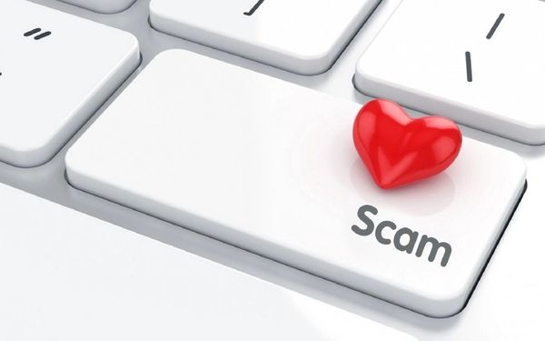 White computer keyboard with the word SCAM on a key and a red heart placed on top of it.