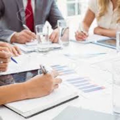 Office employees sitting around a table writing and collaborating.