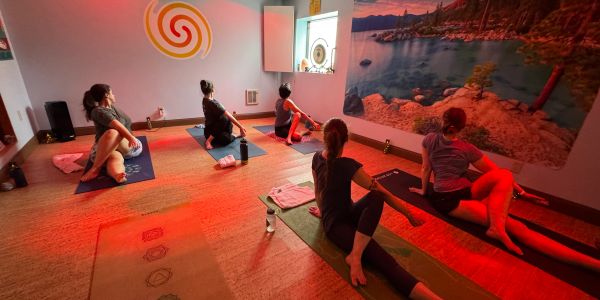 Group yoga session in a warmly lit studio with scenic wall art.