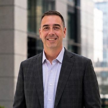 Smiling man in a suit outdoors.