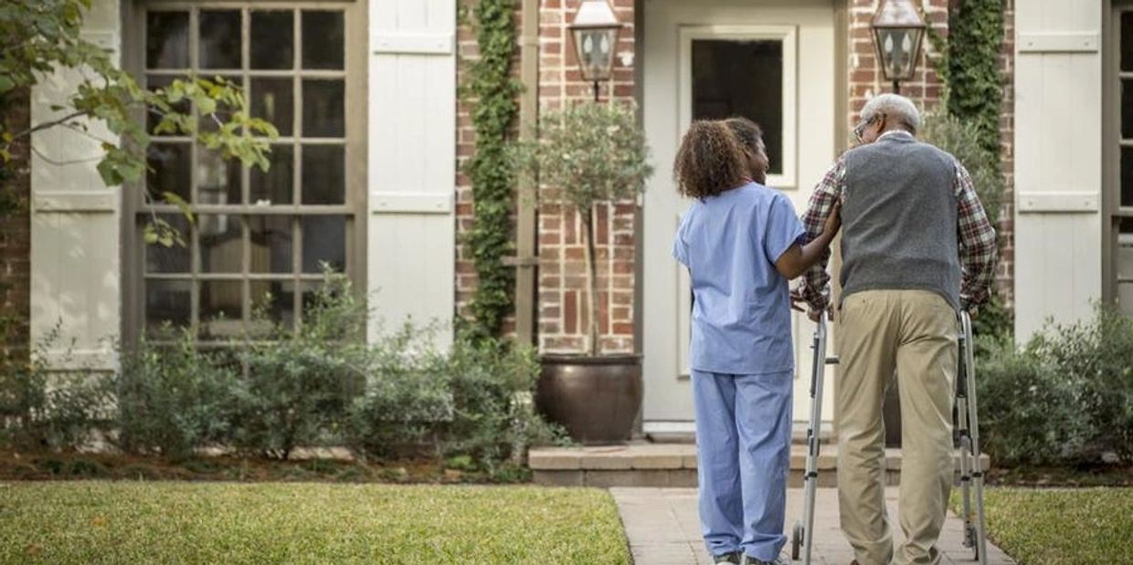 Image of provider assisting elder gentleman while walking