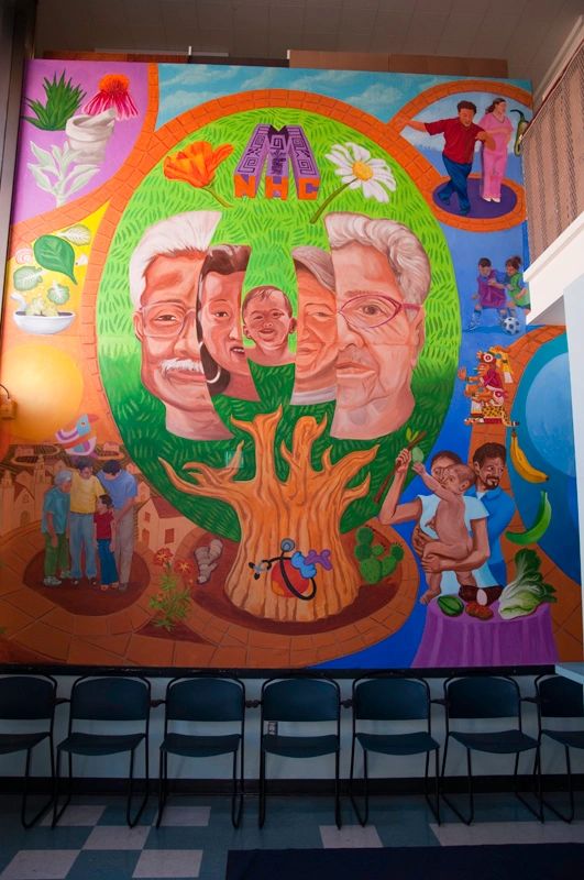 Lobby mural with faces of all ages in a tree surrounded by active people and symbols of good health.