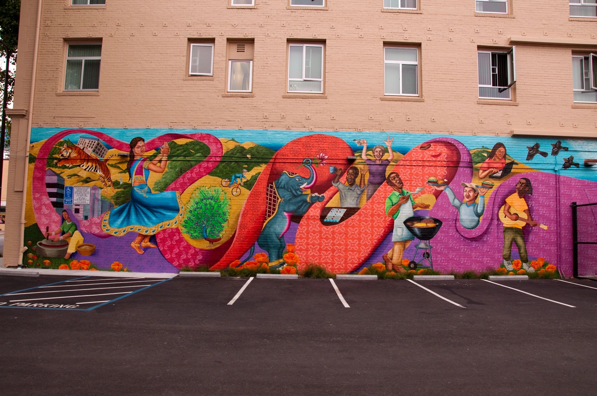 A colorful mural with East Indian cultural symbols, and multicultural figures busy with activities.