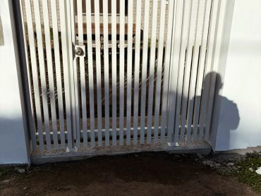 White metal gate with vertical bars in front of a house door.