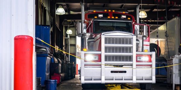 A large red semi-truck inside a dimly lit garage or workshop.