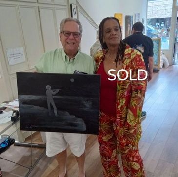 Two people proudly display a sold painting in a gallery setting.
