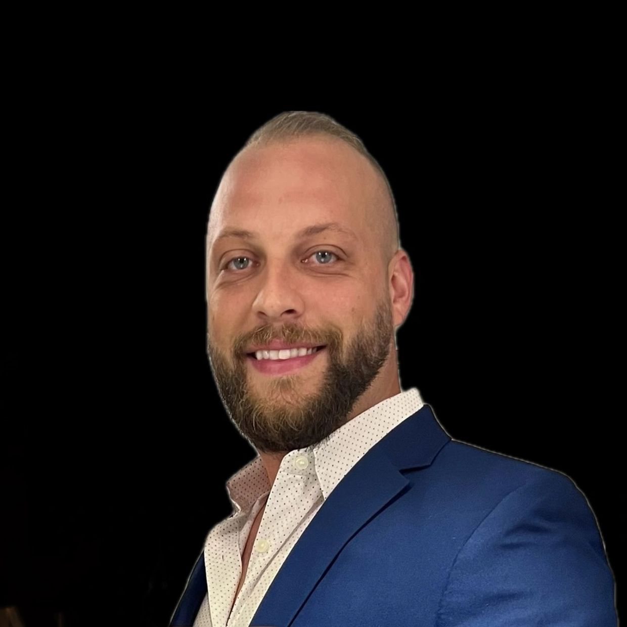 Smiling man in blue suit and white patterned shirt.