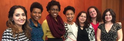 Group of seven diverse women smiling indoors.