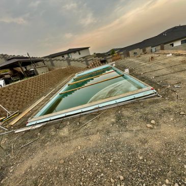 Sunken swimming pool filled with water at construction site.