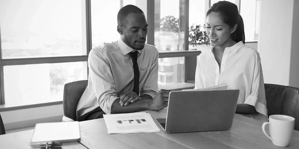 A man and a women at a table looking at a laptop