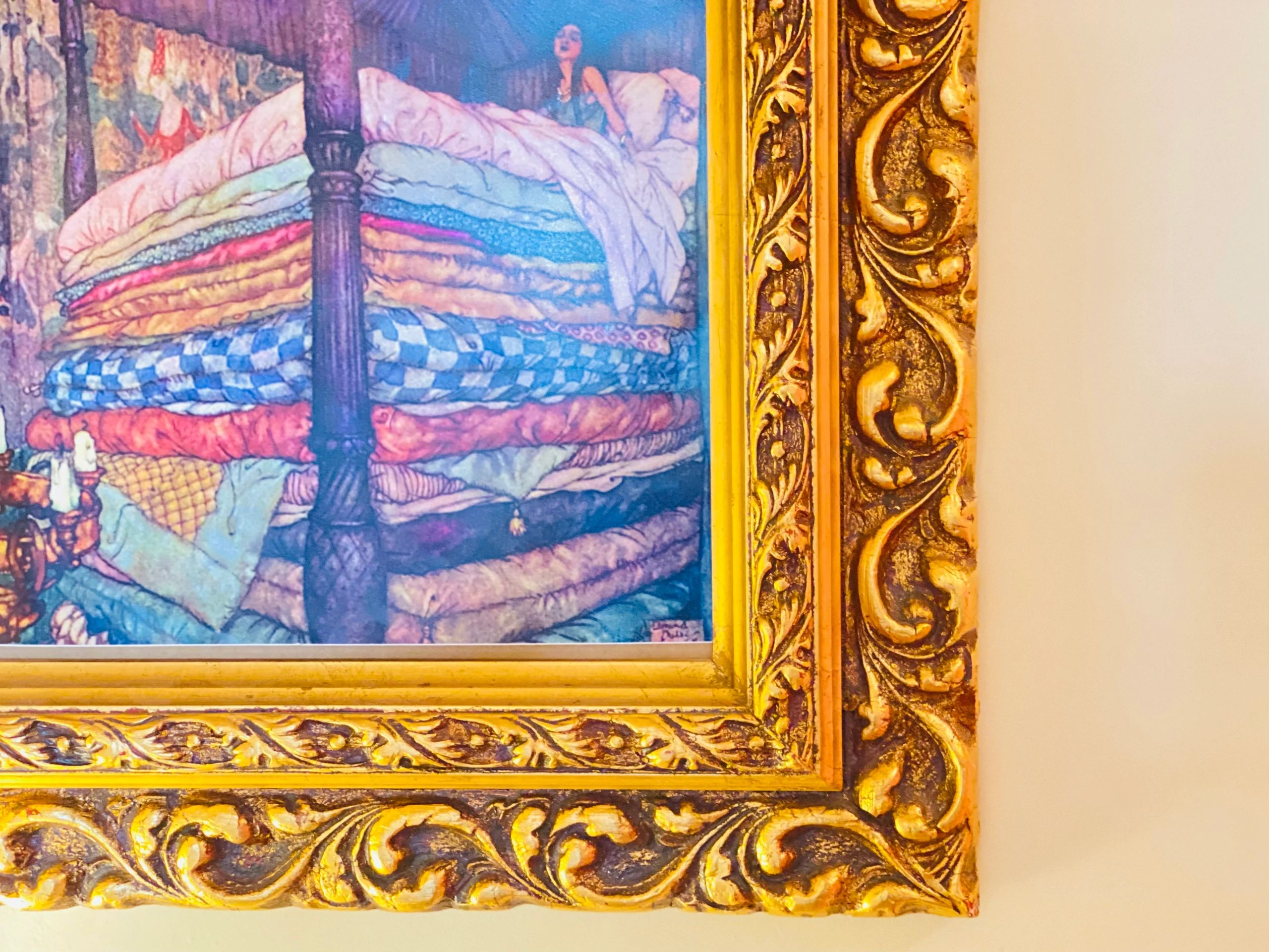 Framed painting of a princess sitting on a stack of mattresses at Princess and the Pea Hotel