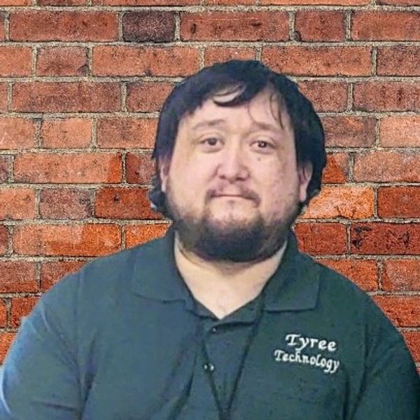 Man in a Tyree Technology shirt against a brick wall.