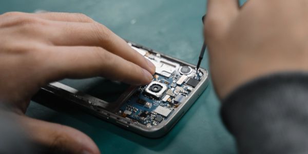 Person repairing a smartphone using a screwdriver.