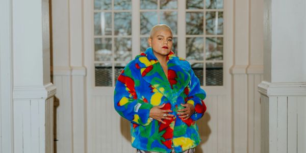 Person in a vibrant multicolored fur coat standing indoors.