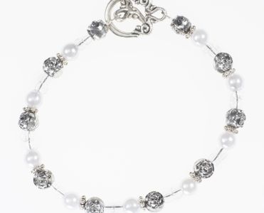 Bracelet has white pearls, silver beads, round clear beads and toggle clasp
