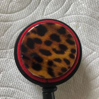 ID Badge reel has cheetah design with red cording on black badge reel