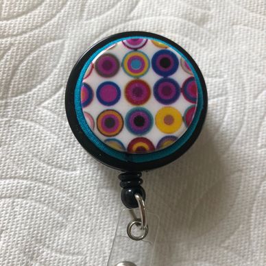ID Badge reel has multiple colored circle design with aqua cording on black badge reel