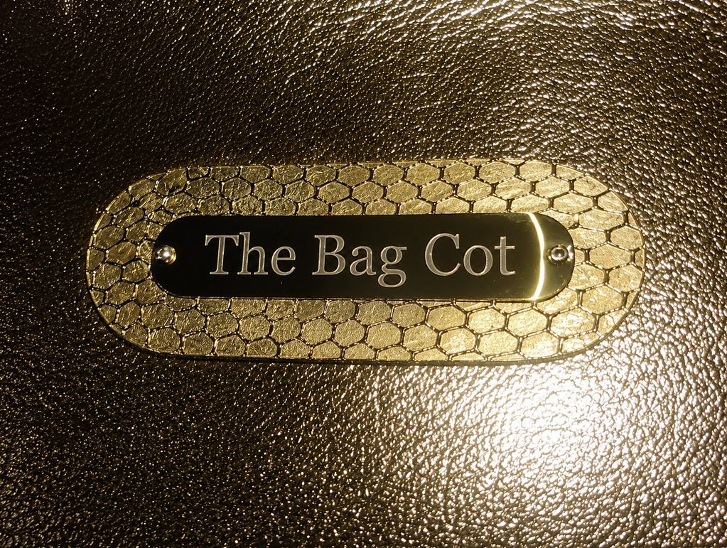 Close-up of a nameplate saying 'The Bag Cot' on textured leather.