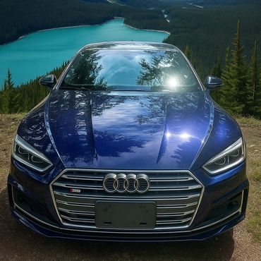 Blue Audi S5 parked near a scenic turquoise lake surrounded by forest.