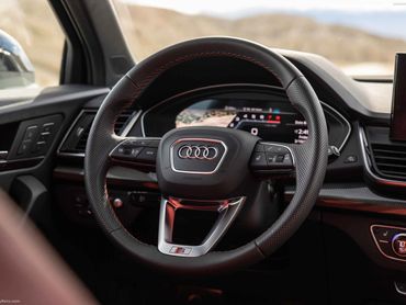 Close-up of Audi S steering wheel with digital dashboard in the background.