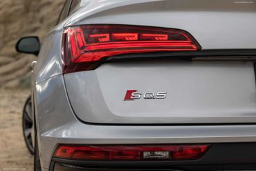 Rear view of a silver Audi SQ5 with illuminated taillights.