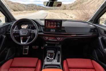 Luxury Audi car interior with red leather seats and advanced dashboard technology.