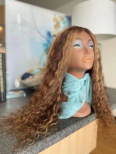 Mannequin head with long curly brown hair and a light blue scarf.