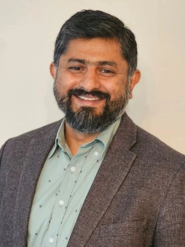 Smiling man with beard and jacket.