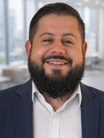 Smiling man with beard in business attire.
