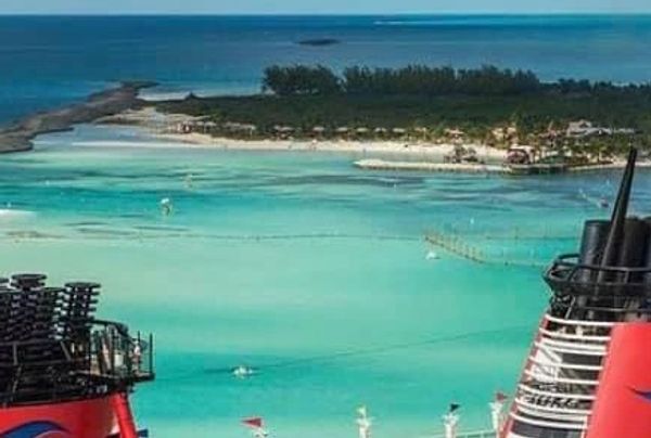 View of a tropical island and turquoise sea from a cruise ship deck.