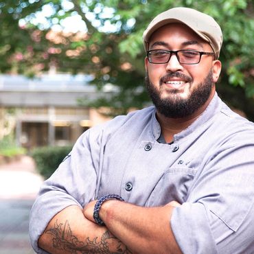 Portrait of a young man in a courtyard with arms crossed looking at camera