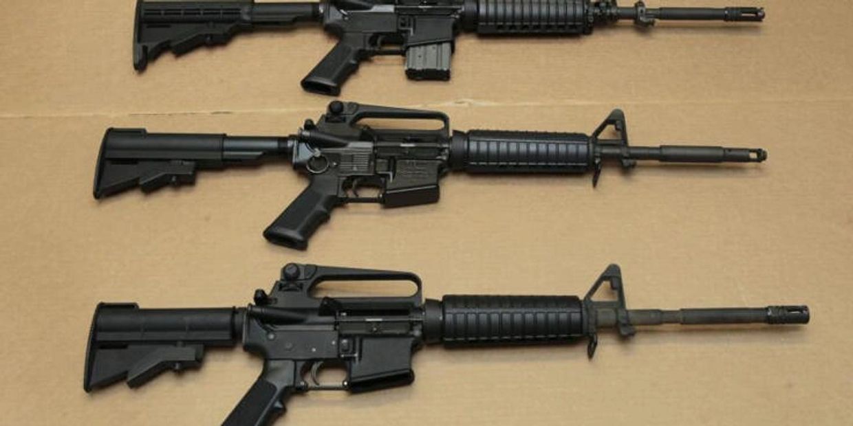 Three black rifles on a beige surface.
