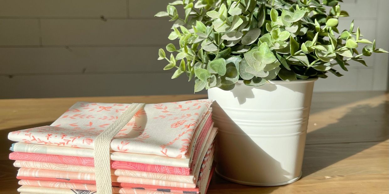 pink and white fabric on farmhouse wood table with green plant in white can with ship lap background