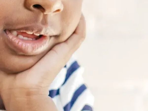 Child's mouth with hand on cheek.