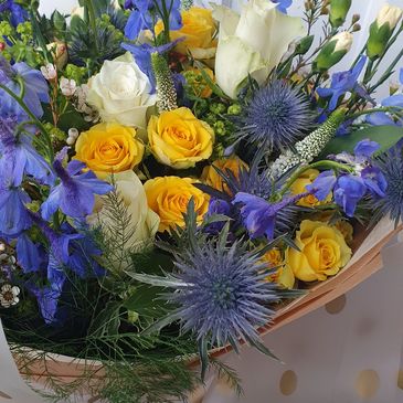 Colorful bouquet with yellow roses and blue flowers.