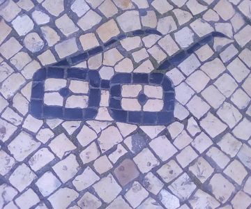 A mosaic in a pavement depicting a pair of glasses. Rato,Lisbon. Photo by Richard Price.
