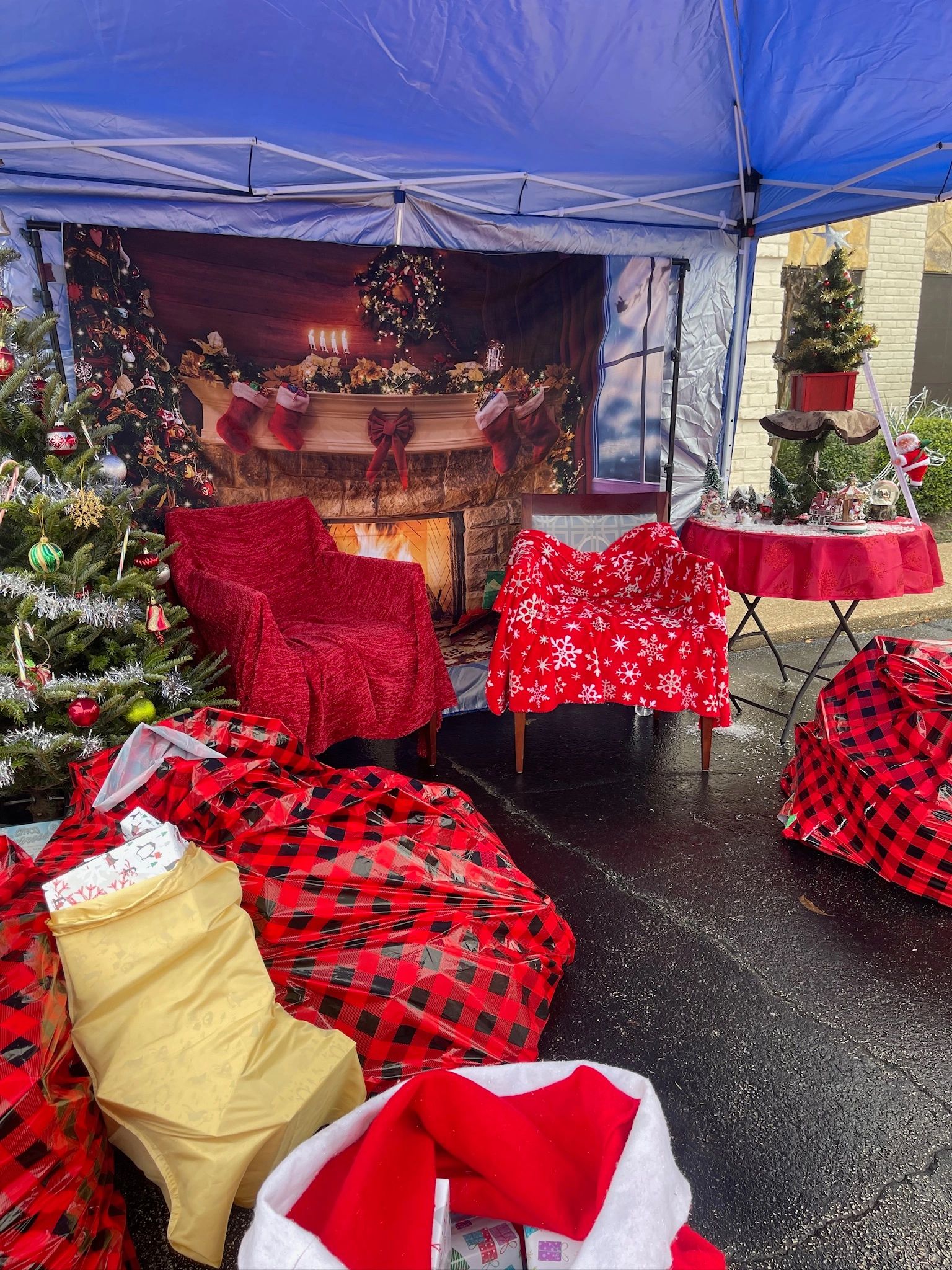 Cozy outdoor Christmas setup with decorated tree, wrapped presents, and festive chairs.