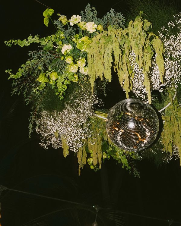 Lush greenery around disco ball suspended over dance floor at wedding in Sayulita Mexico