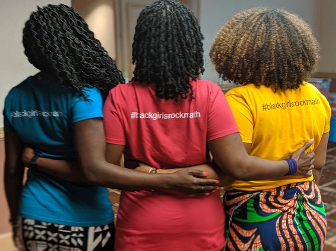 Three black women turned to the back with arms linked.
