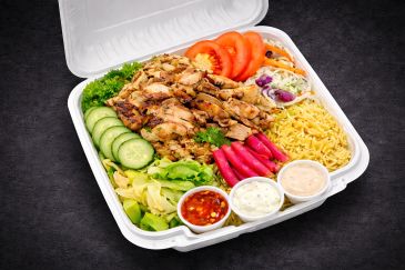 Grilled chicken and vegetables in a takeout box.