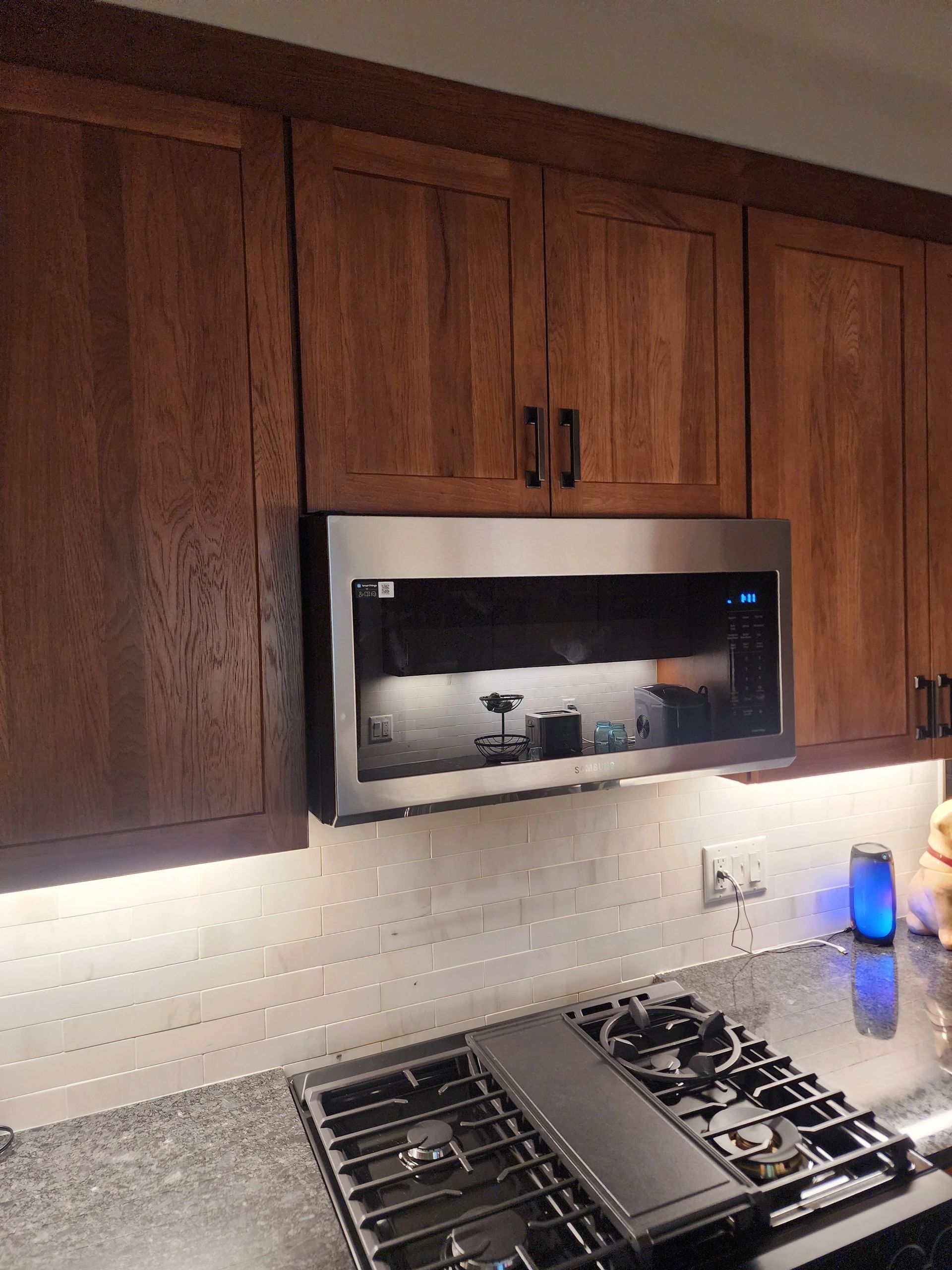 Modern kitchen with wooden cabinets, stainless steel microwave, and gas stove.