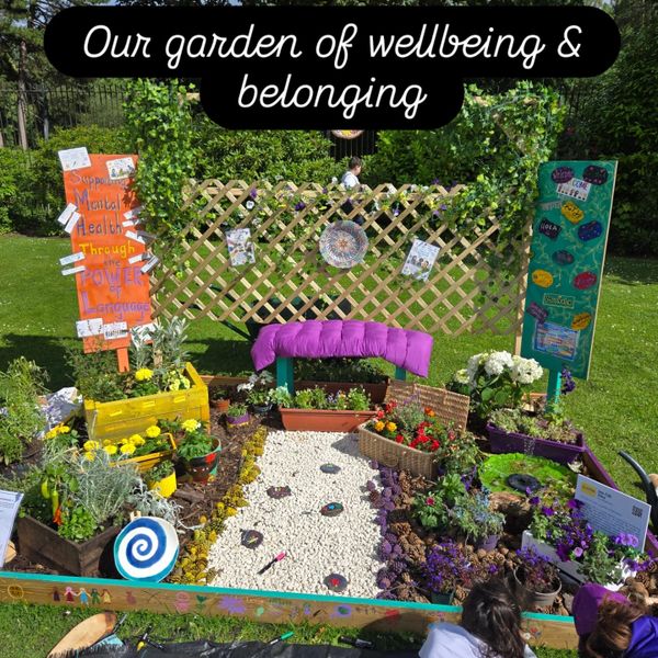 A vibrant garden display promoting wellbeing and belonging with colorful flowers and signs.