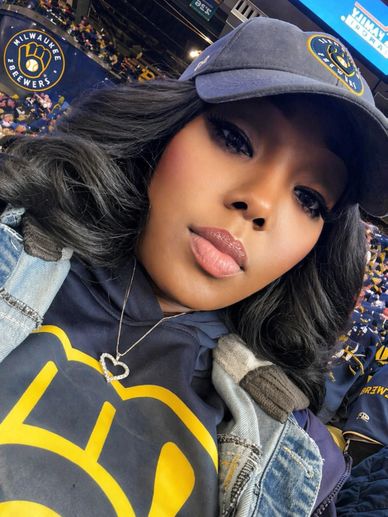 Woman wearing Milwaukee Brewers gear at a baseball stadium.