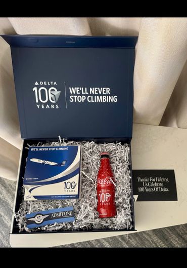 Delta Airlines 100 years celebration box with model plane and Coca-Cola bottle.