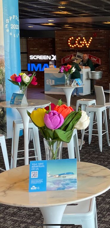 Colorful tulips in vases on white tables at a film festival lounge.