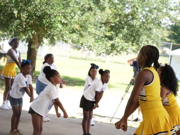 Group of young girls and cheerleaders practicing outdoors.