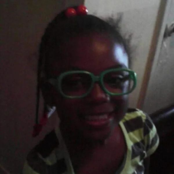 Smiling girl wearing large green glasses and a striped shirt.