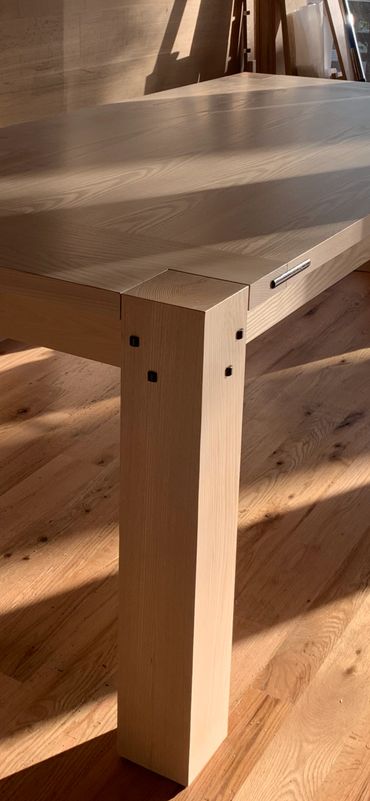 Custom furniture ash dining table in oak clad room.