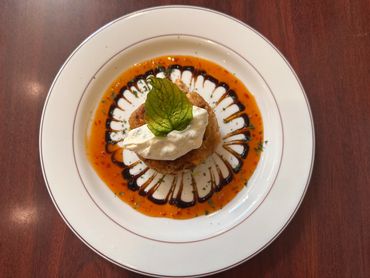 Gourmet appetizer with sauce, cream, and a fresh basil leaf garnish.